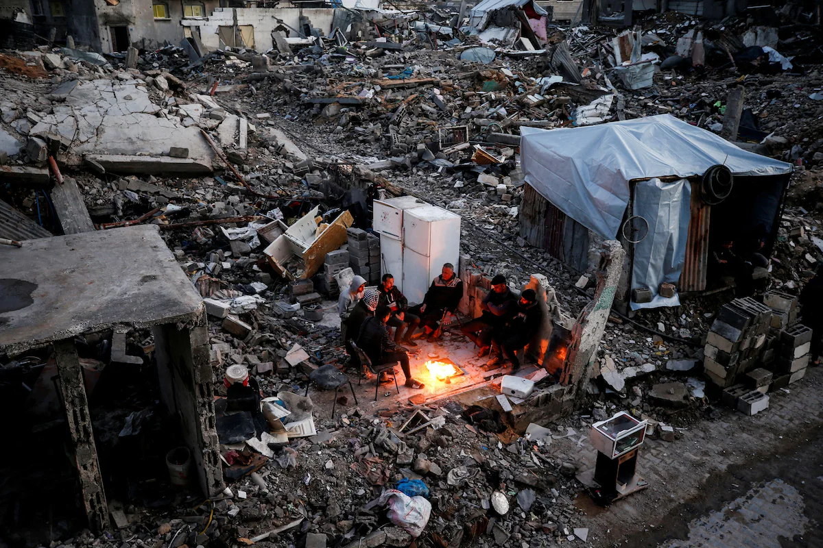 Палестинці збираються навколо багаття серед уламків зруйнованих будівель у таборі для біженців Джабалія на півночі сектора Газа 13 лютого